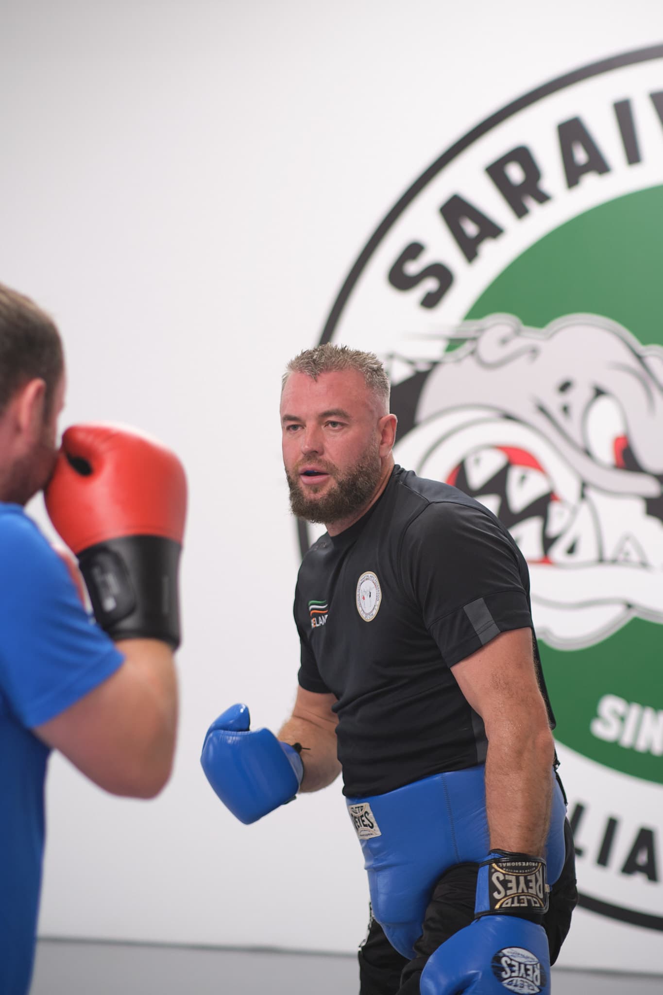 Coach assisting student with mitt work — technique refinement